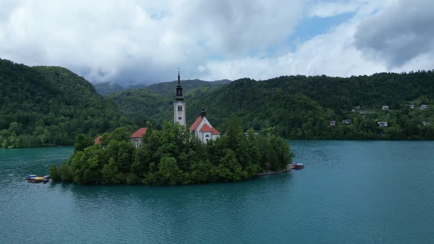 An island in the middle of a lake featuring a church illuminated by the bright midday sun