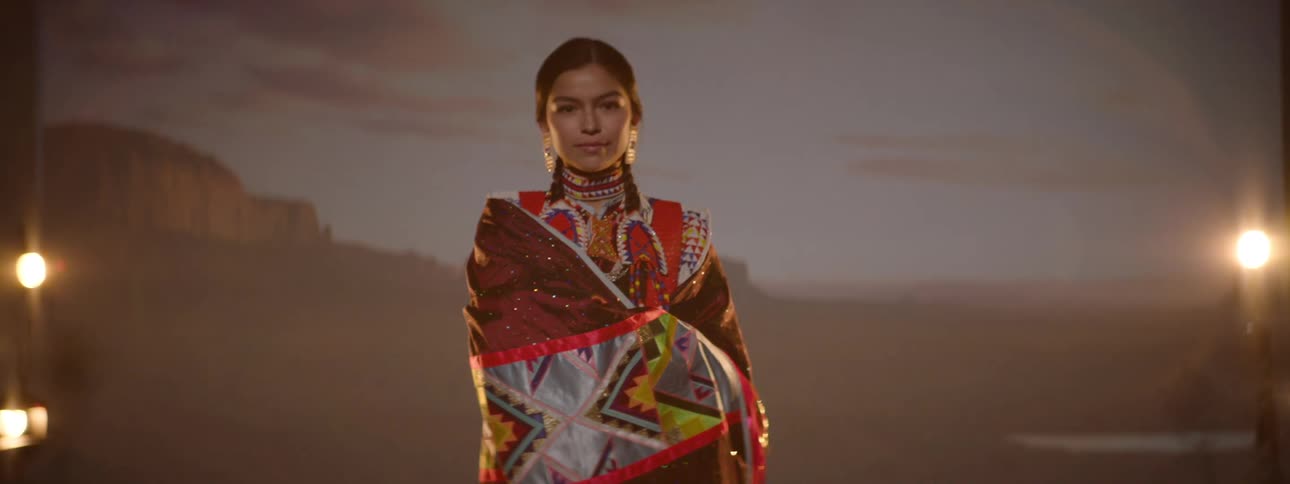 An american indian woman wearing traditional attire standing on a stage