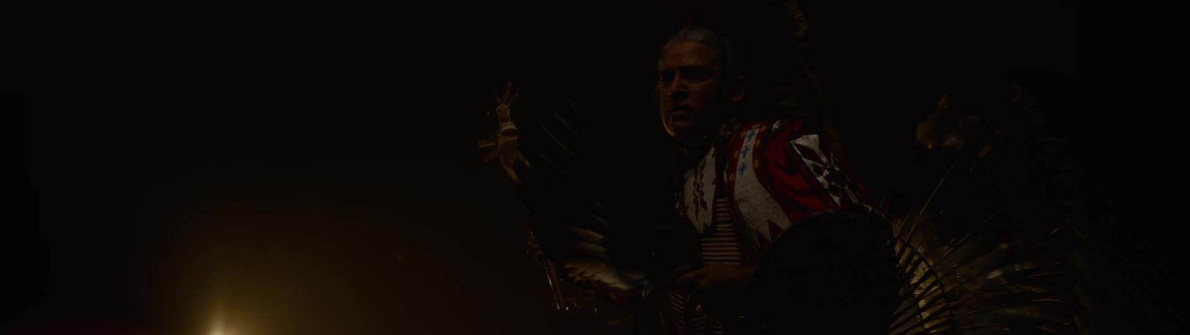 The man carrying a scepter is dancing on a dark stage