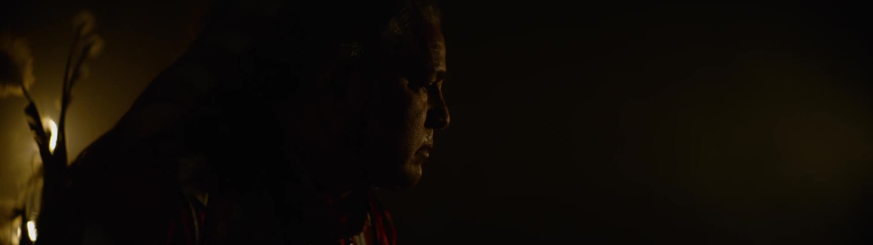 A man wearing a headdress slowly looks up