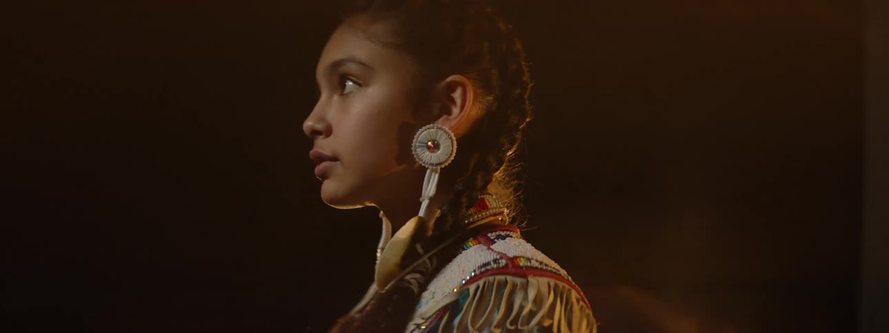 A woman steps forward while wearing indigenous clothing