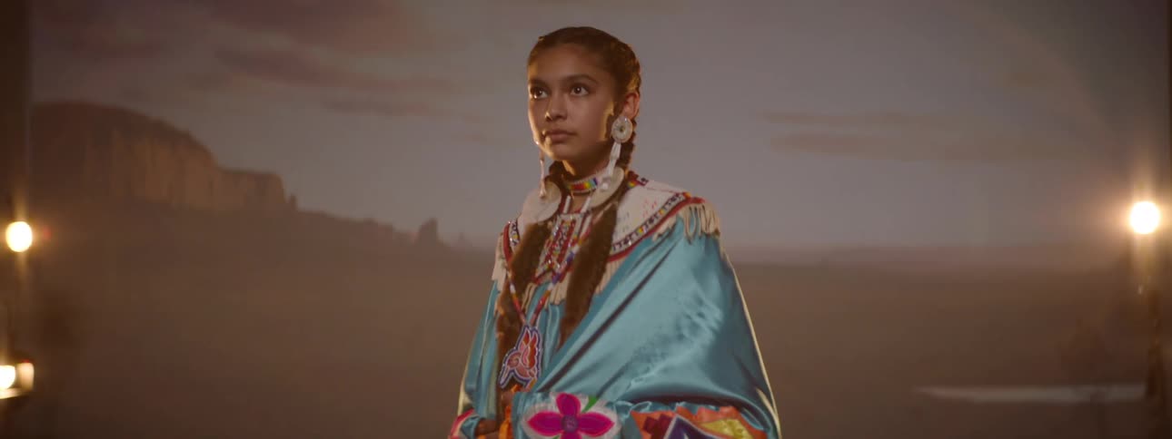 Young teenager wearing traditional indigenous costume on a lit stage