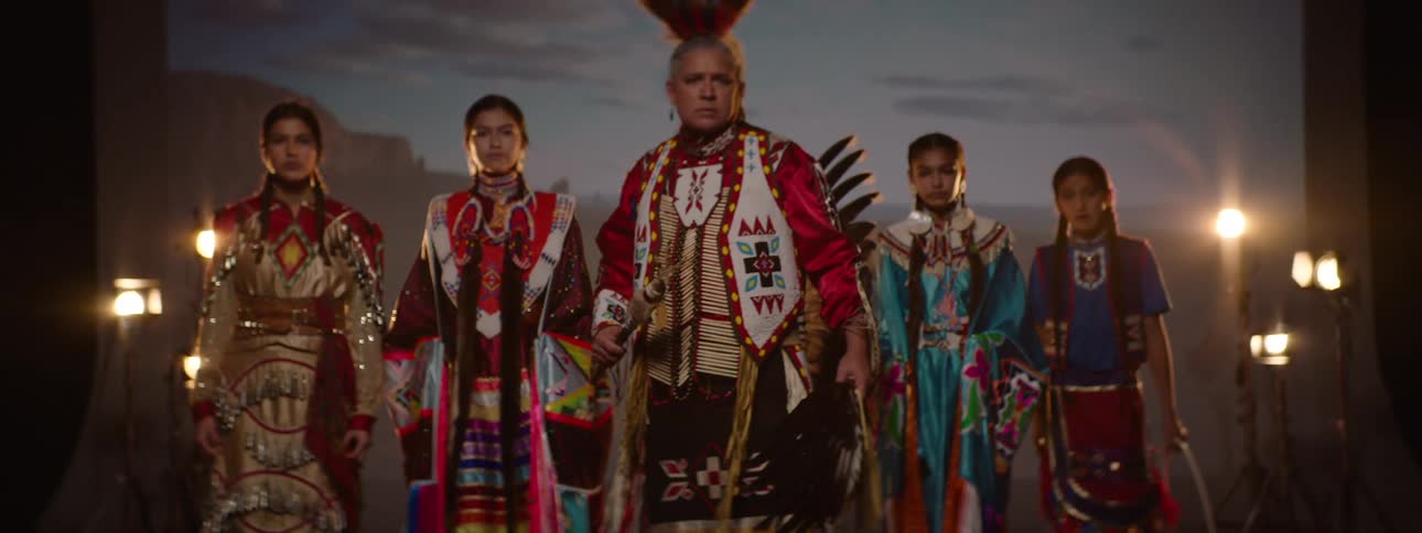 A group of native americans wearing traditional attire standing together on a stage