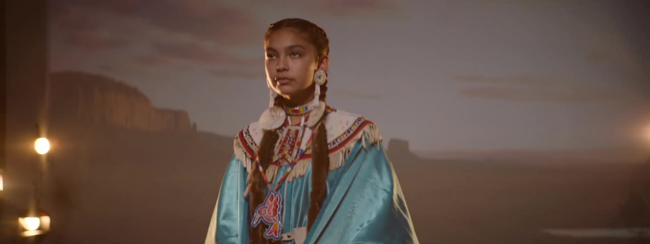 A young woman wearing native american clothing posing for photos in a studio