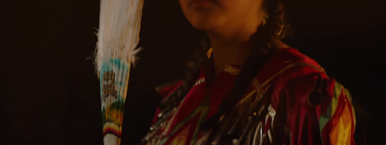 A girl is wearing a costume and holding feathers