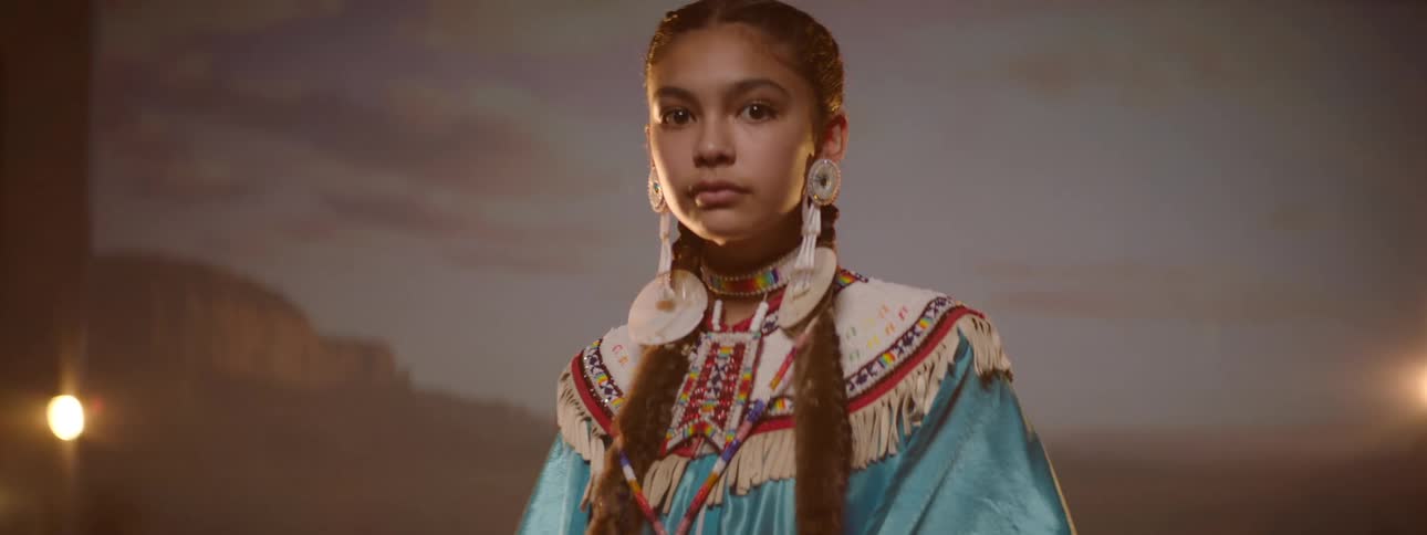 A native american teenager wearing traditional clothes in a photo studio