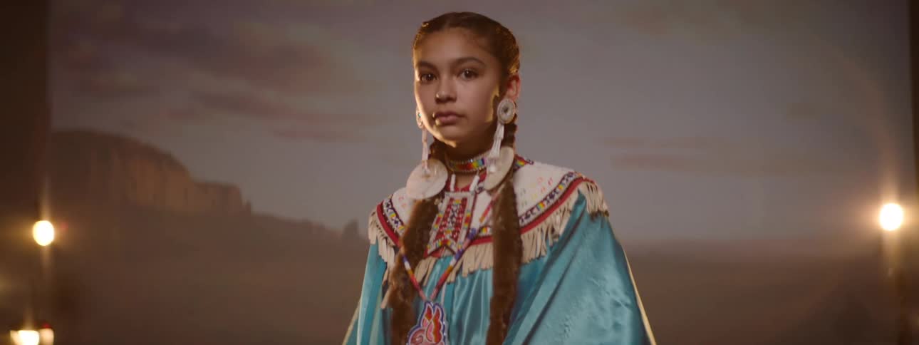A native woman is posing in full regalia