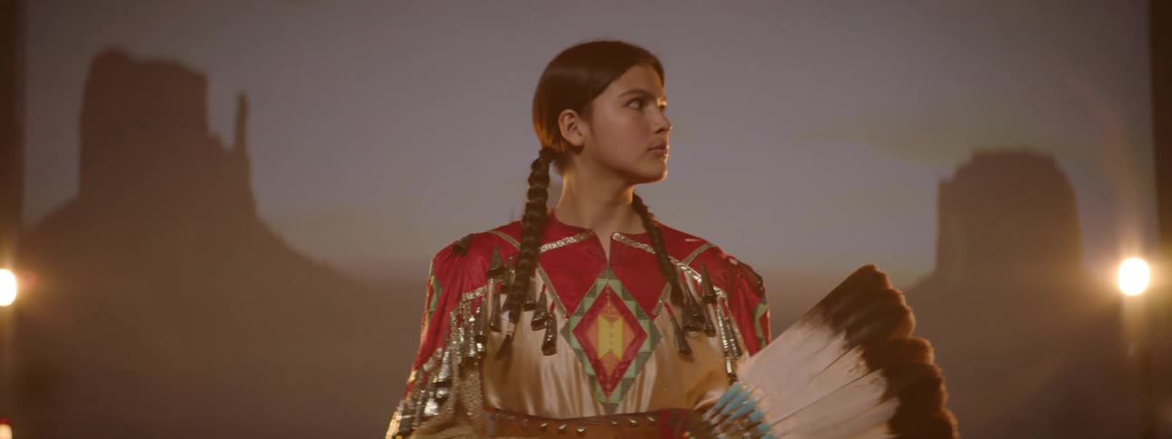 The girl poses on stage holding feathers