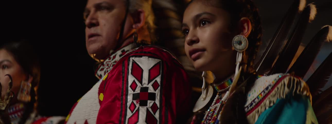 A tribe in costume are posing together on a stage