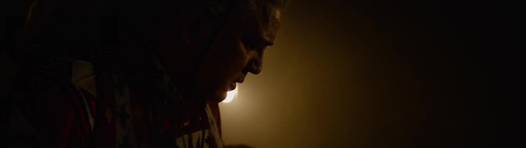 A man stands in the dark wearing a costume