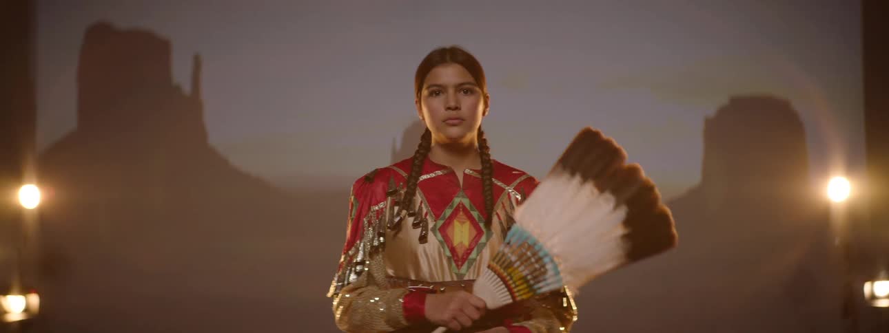 Girl in traditional indigenous costume holding a feather fan