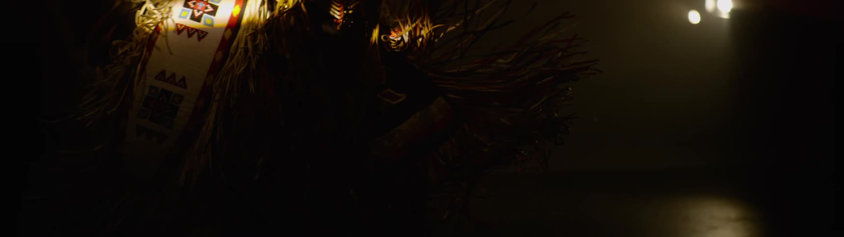 A person wearing a costume moves on the dark stage