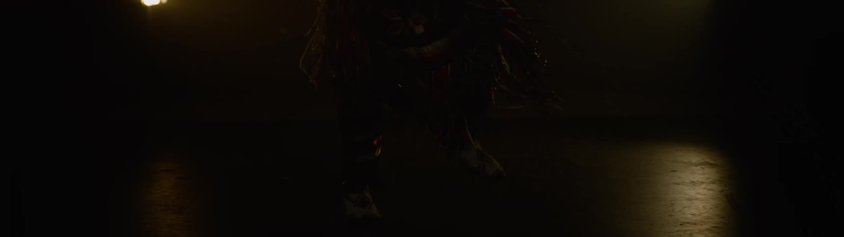 A person dances on the dark stage