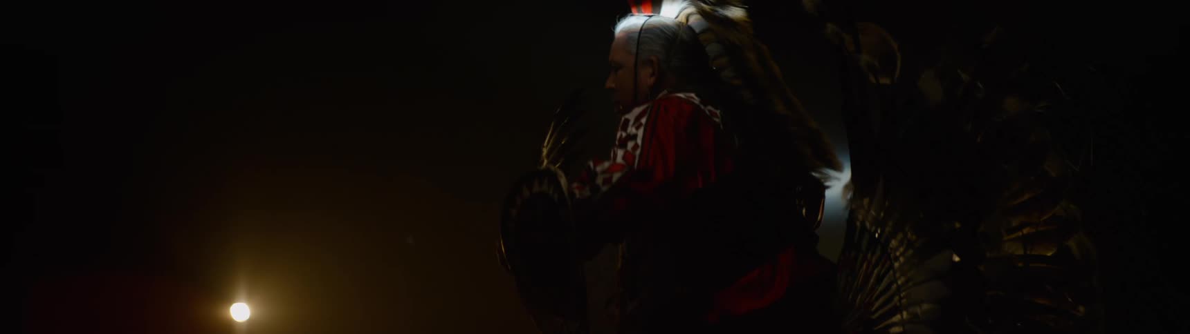 An american indian man on a stage wearing traditional native attire