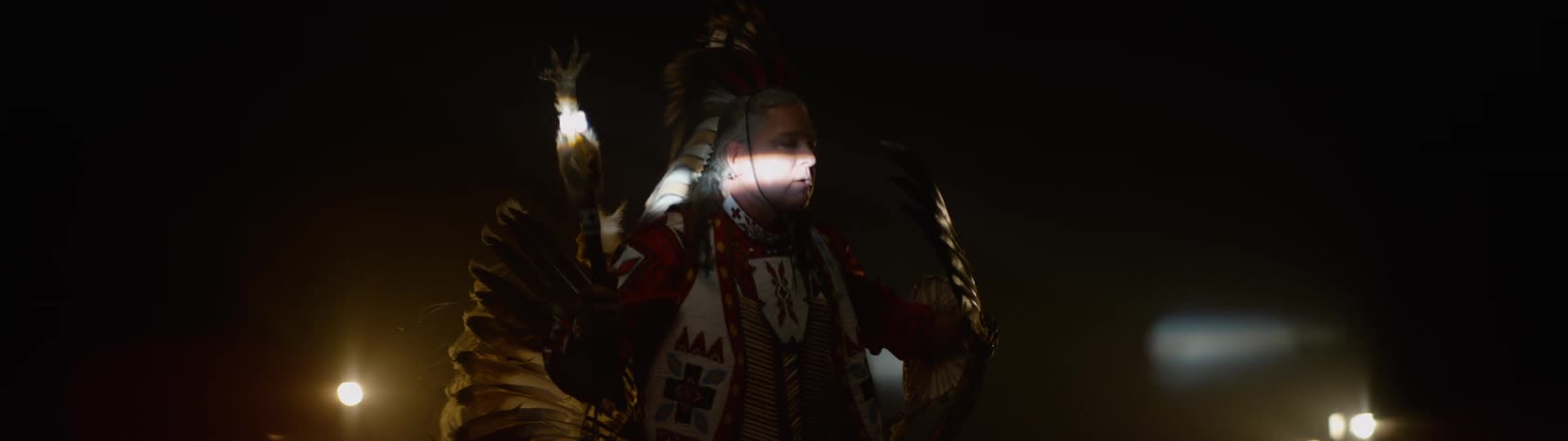 Man dressed in traditional indigenous attire in an indoor setting