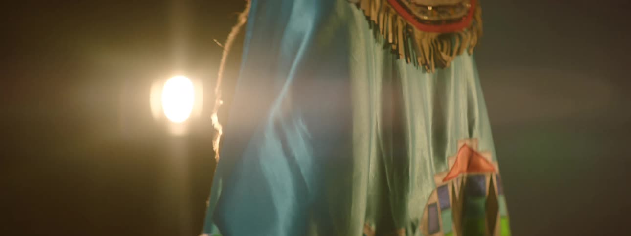 Young native american woman wearing a richly decorated dress stands near a photo backdrop