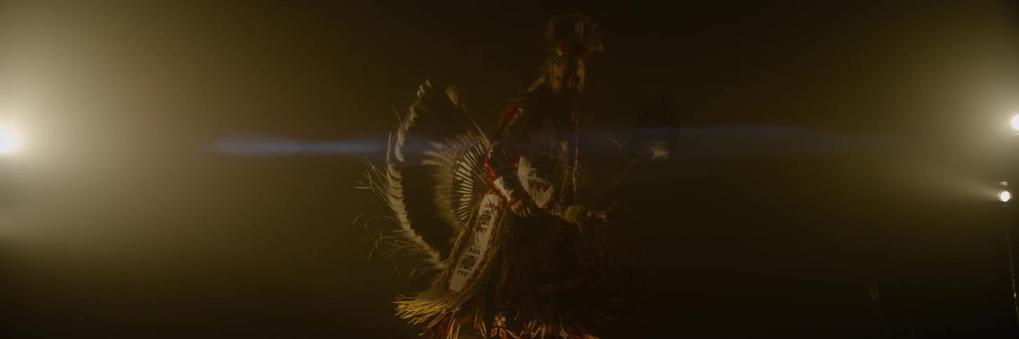 A man in a feathered costume is dancing on stage