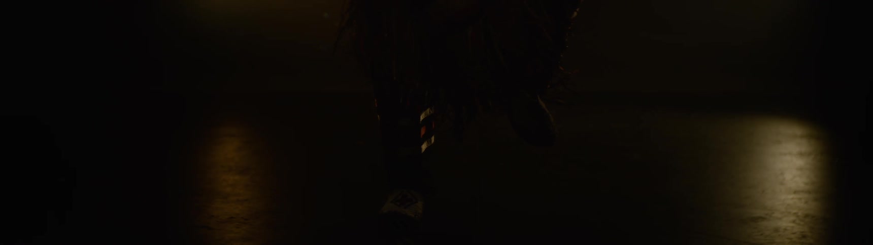 Closeup of feet dancing on a dimly lit stage adorned in traditional native american attire