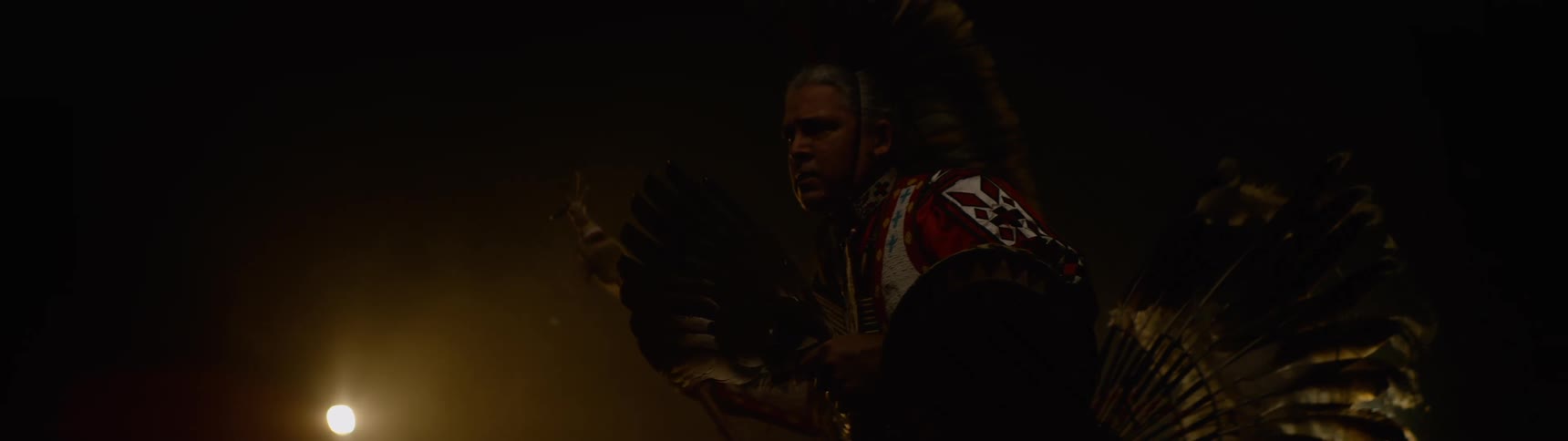 Man in traditional indigenous clothing performing