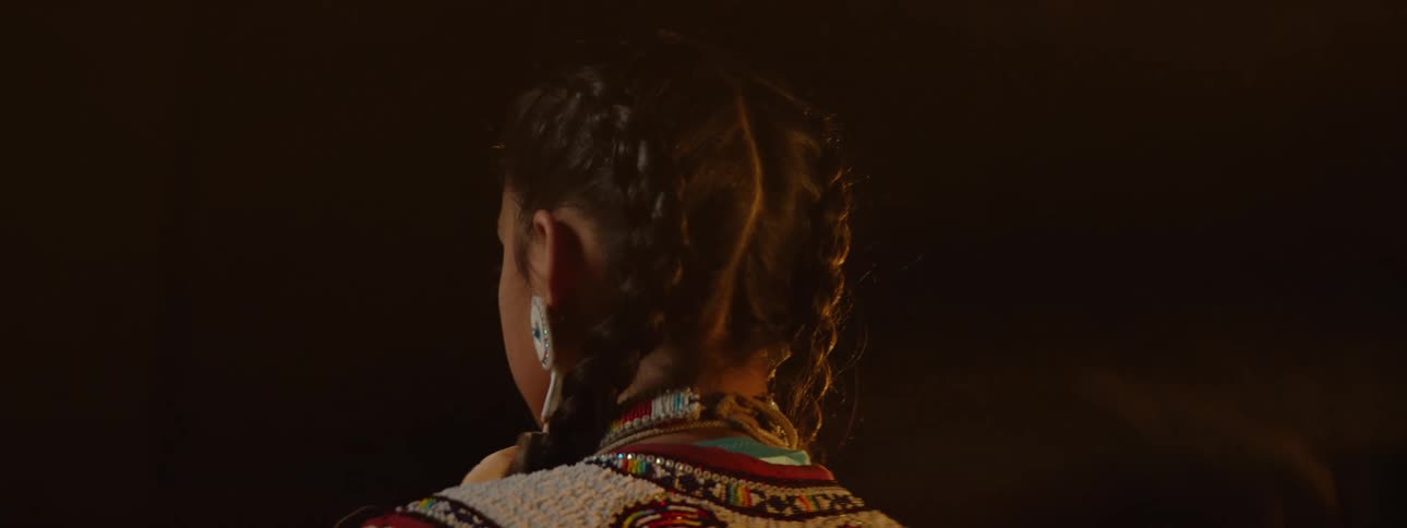 A woman in a traditional native american dress is filmed