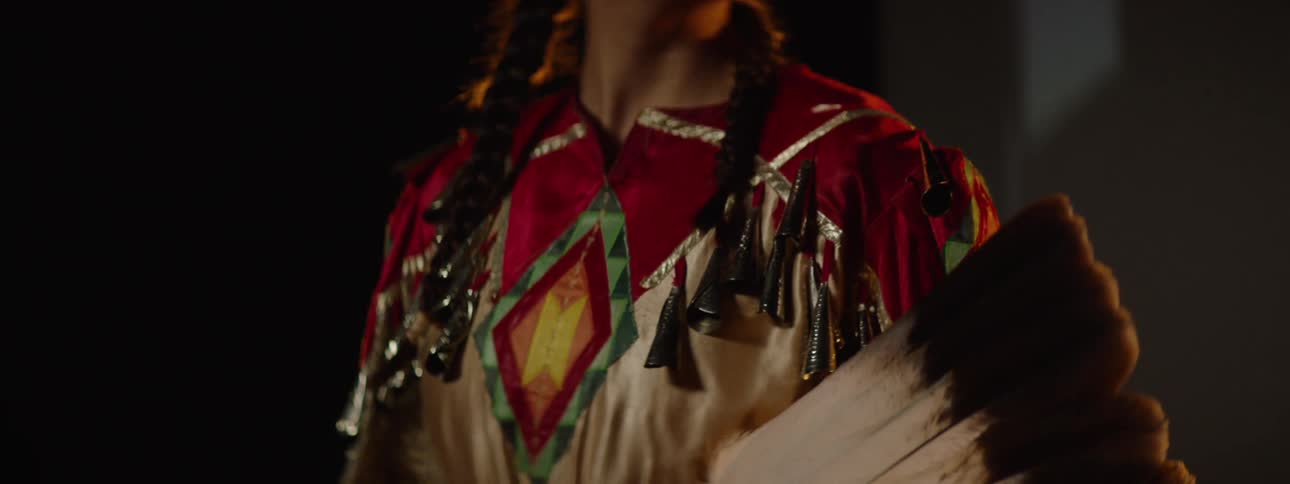 A young native american woman wearing indigenous clothes holding a feather fan