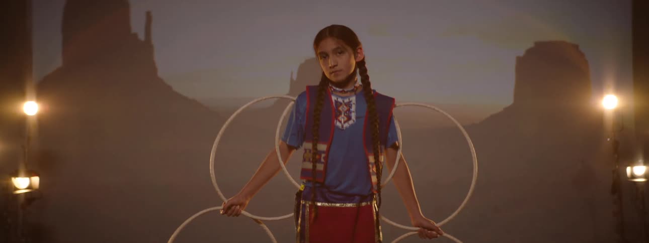 Girl in a studio wearing traditional indigenous clothing holding bows