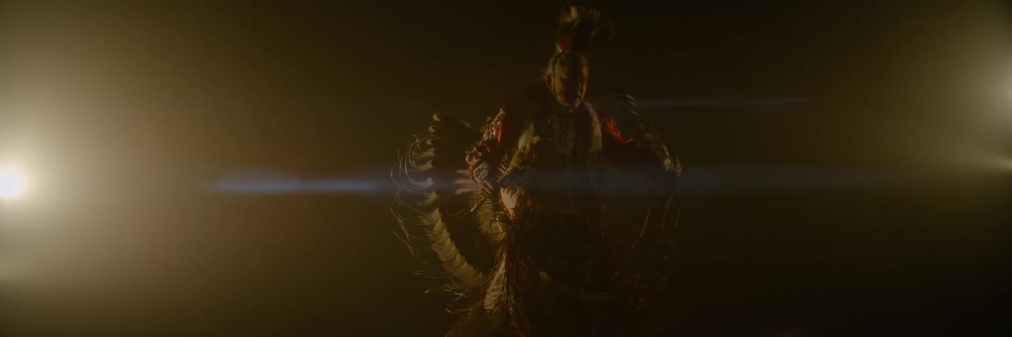 A native in costume is dancing and swinging his arms