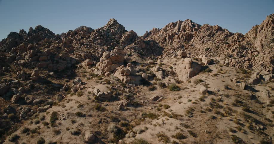 A rocky desert landscape with rugged mountains under clear blue sky
