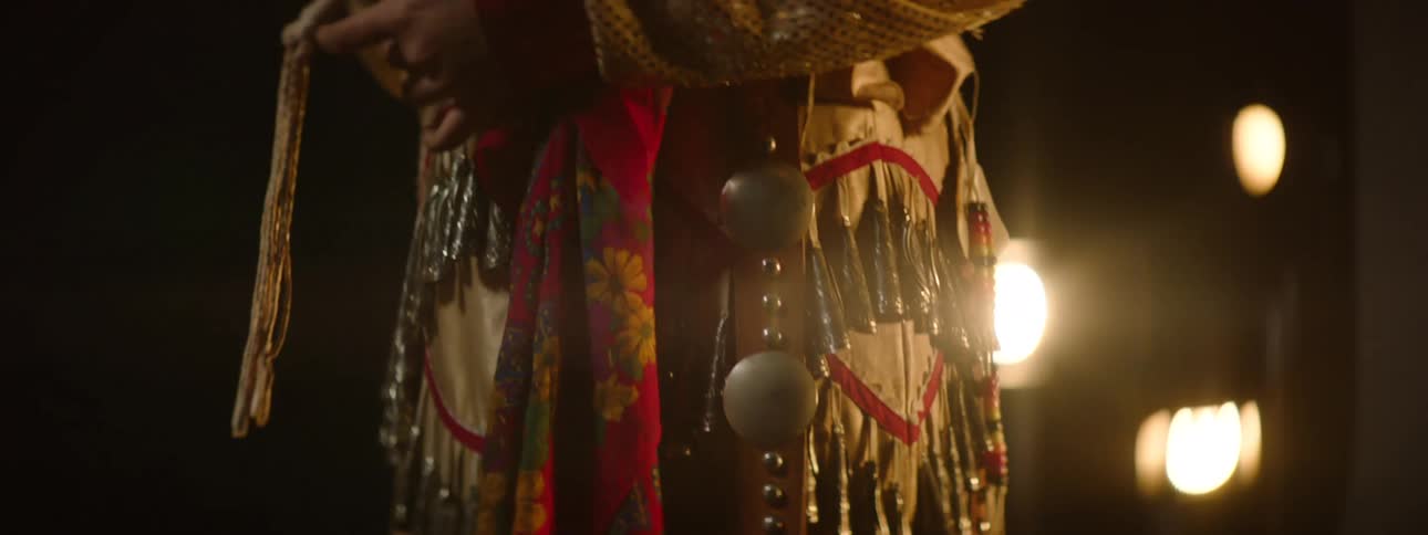 Person in an indoor space wearing traditional indigenous clothing