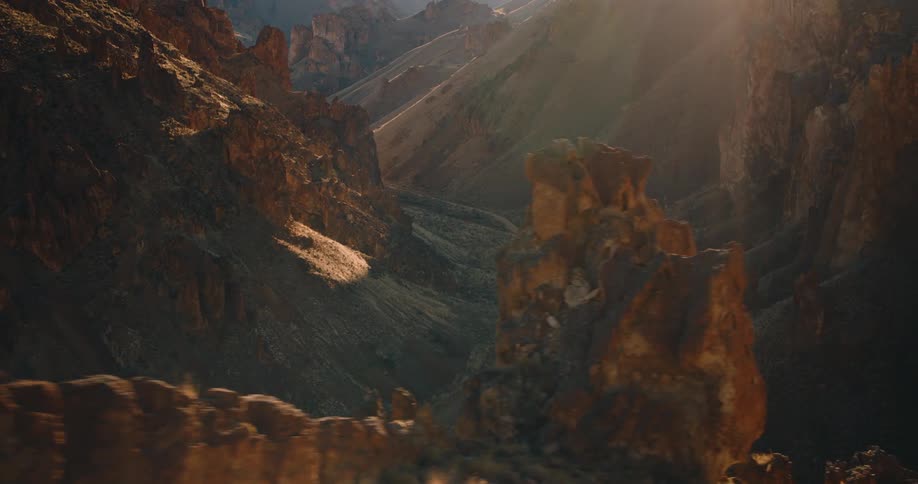 A narrow dirt road winds through rugged sunlit canyon cliffs