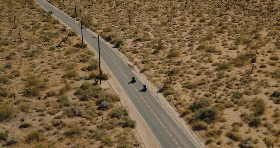 Two people riding motorcycles on a freeway at midday