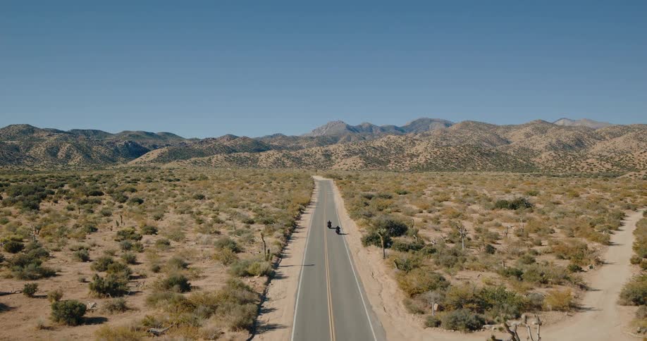 Two men riding motorcycles on a freeway on a sunny day