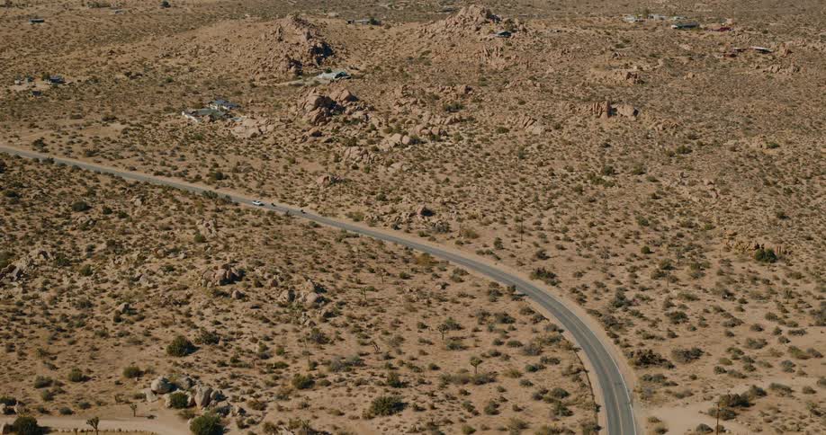 Aerial view of two motorcycles and a truck traveling the opposite direction on a desert highway during the day