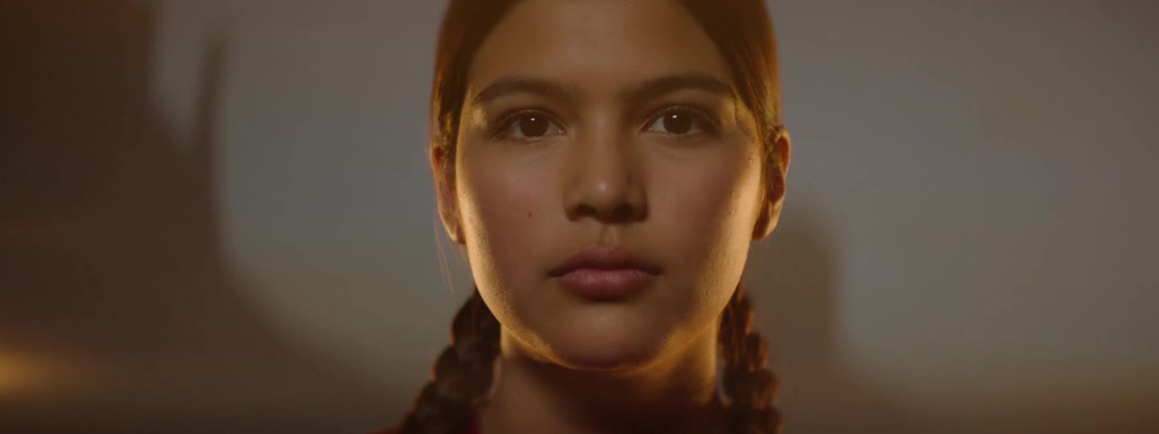 A native american teenage girl lowers a feather fan that was covering her face revealing her features