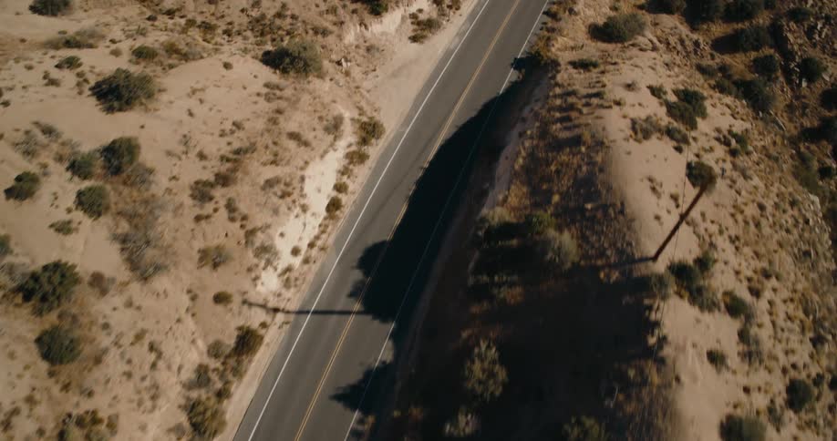 Aerial of an empty highway with hills on both sides at daytime
