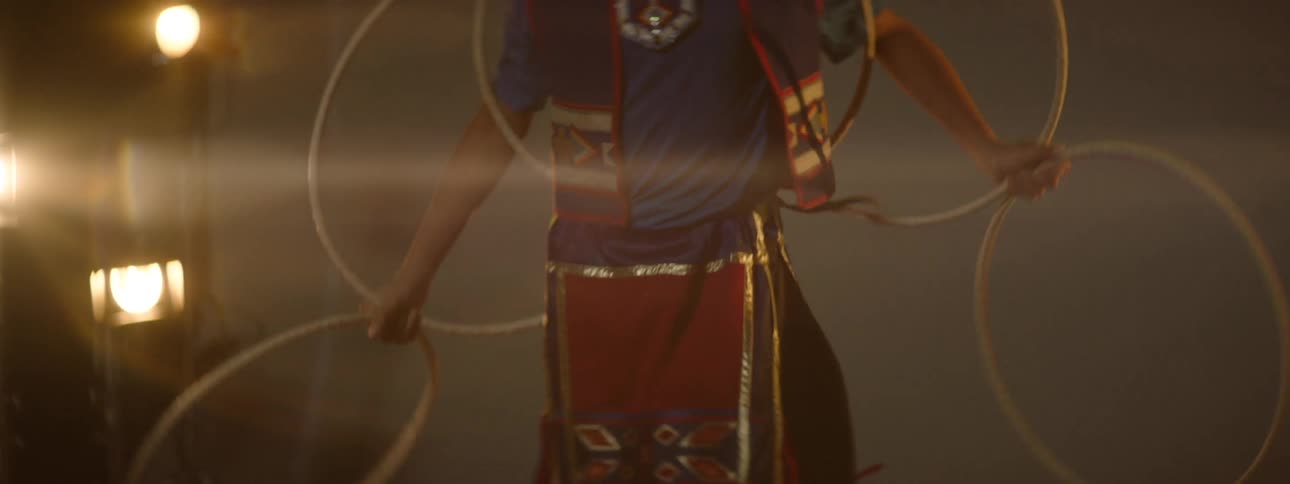 A girl is dancing with hoops on the lit stage