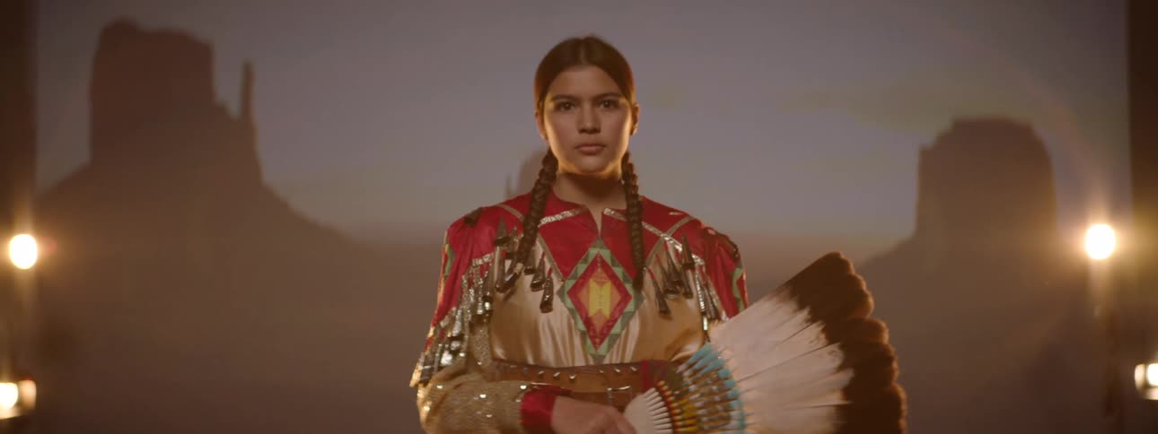 A girl reveals her face by moving the feathers away