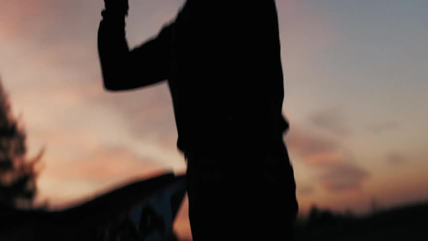 A motorcycle rider putting on a helmet preparing for a ride as the morning sunlight begins to rise