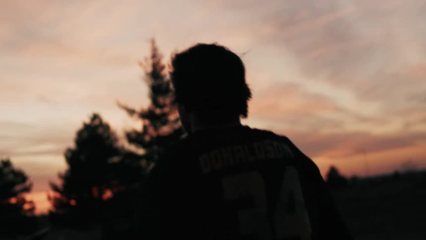 A man walks over to his dirt bike at sunrise