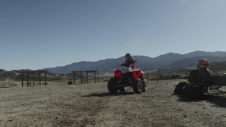 A helmeted rider on a four-wheeler rides off