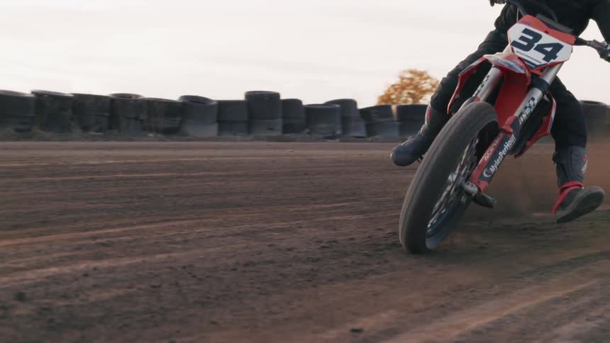 A motorcycle racer wearing a helmet rides through a curve at midday
