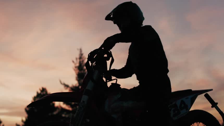 Silhouette of a person wearing a helmet sitting on a motorcycle