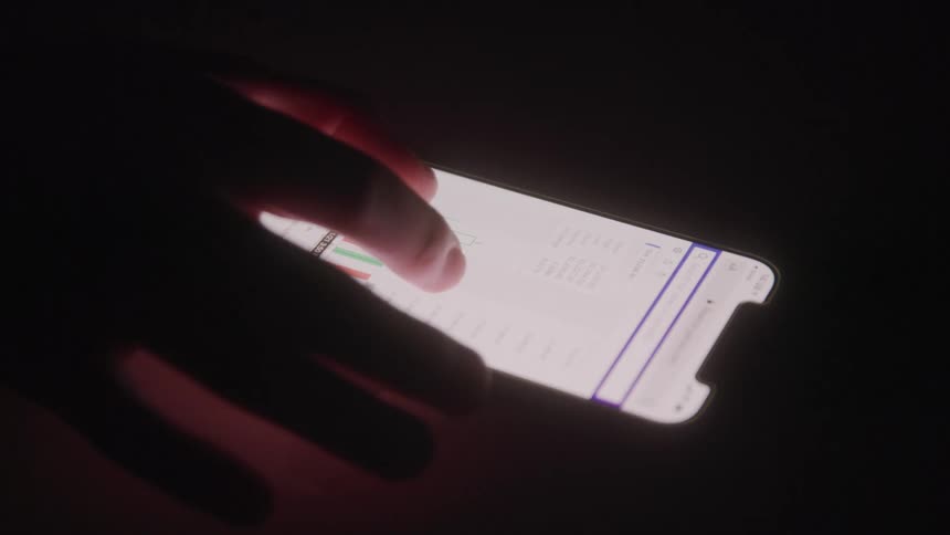 A person using a cellphone and viewing bar charts in binary options
