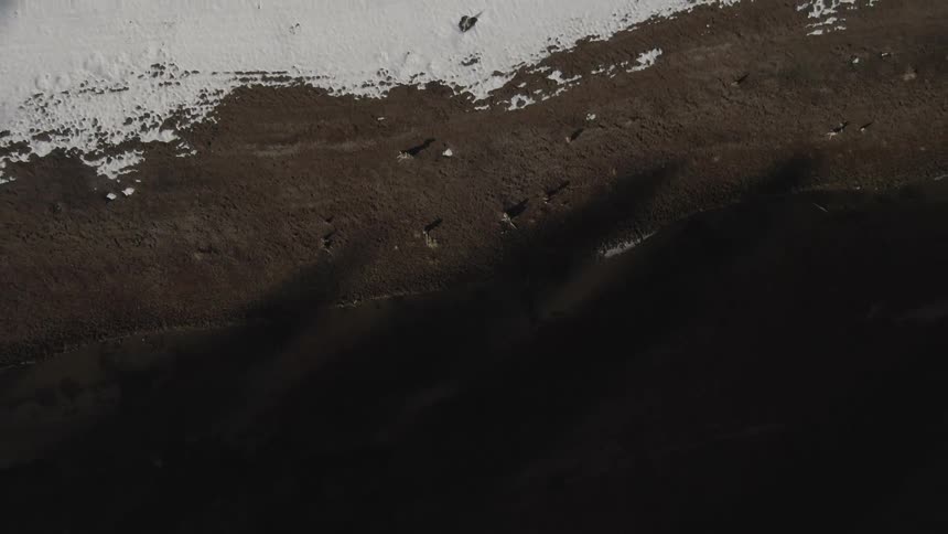 Separation line between snow covered ground and a barren dirt terrain