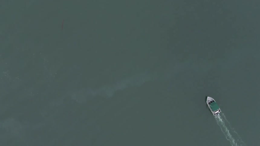 Aerial of a boat moving across the sea surface in daytime
