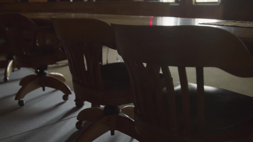 Dimly lit conference room with vintage wooden chairs lined around a large table