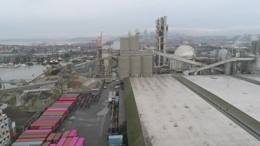 Aerial view of an industrial port facility with shipping containers and large factory structures