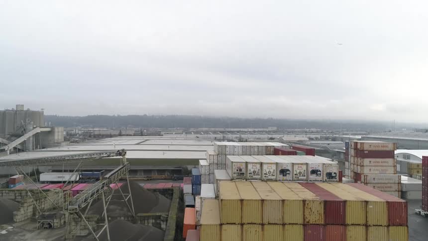 Shipping containers stacked together in an industrial area under a clouded gray sky