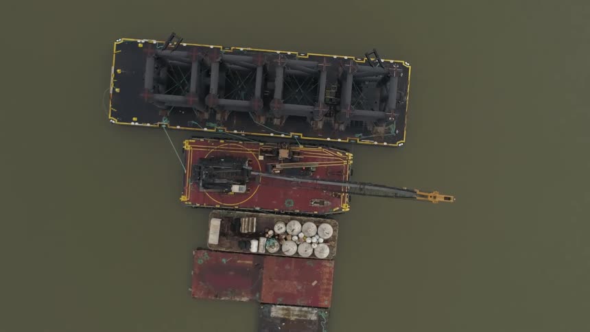 A barge has a large crane on it in the water