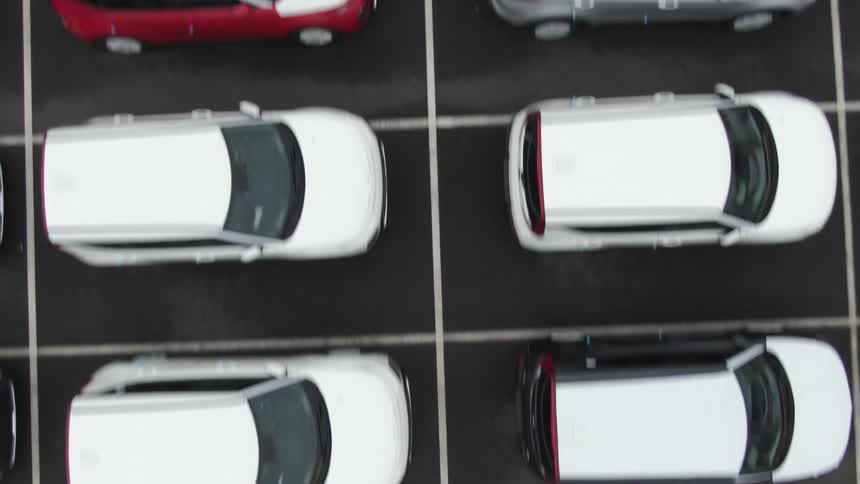 Aerial of a filled parking lot filled with various stationary vehicles during the day